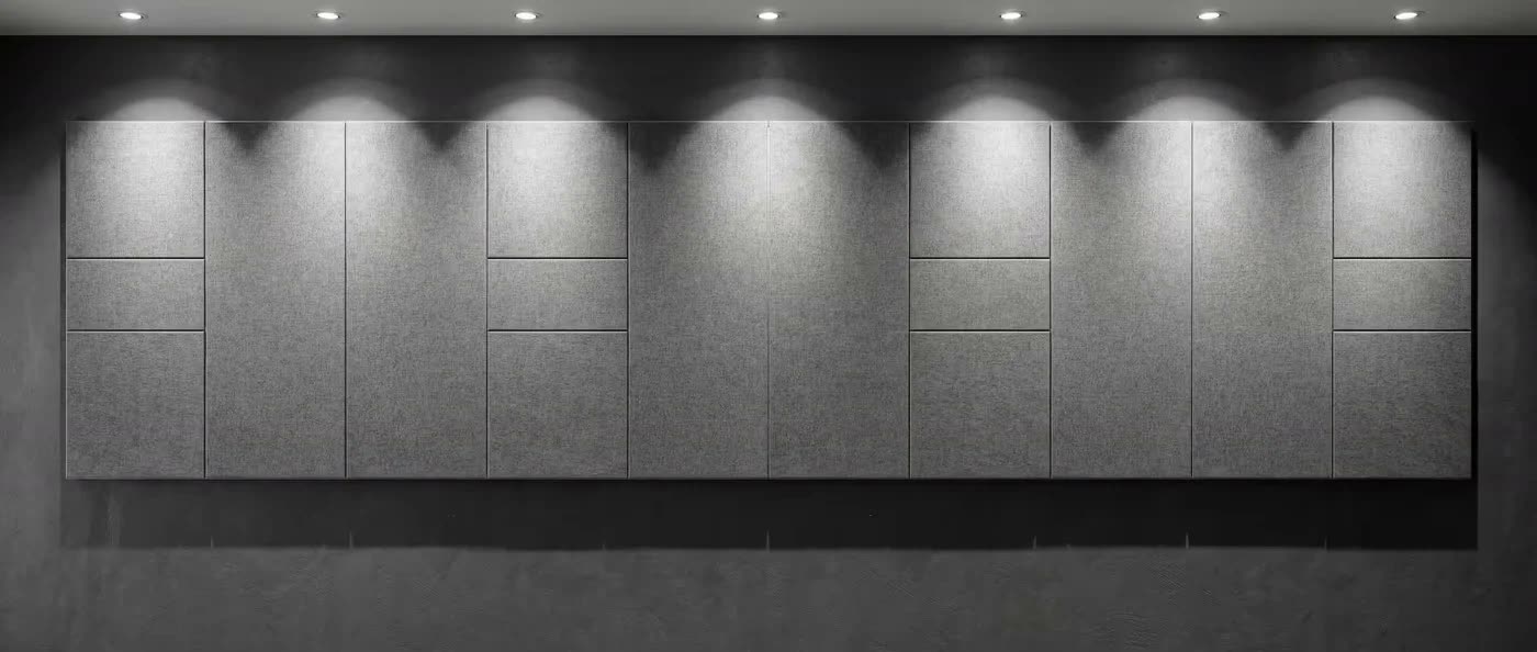 Duvara monte edilmiş gri kumaş kaplı dikdörtgen akustik panel dizisi, üstte spot aydınlatmalarla