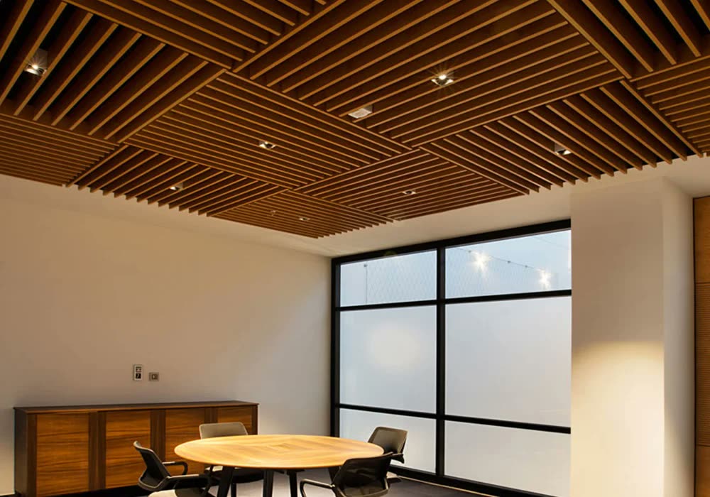 Toplantı odası tavanında geometrik desenli ahşap çıta lineer baffle sistemi, spot aydınlatmalı, yuvarlak masa