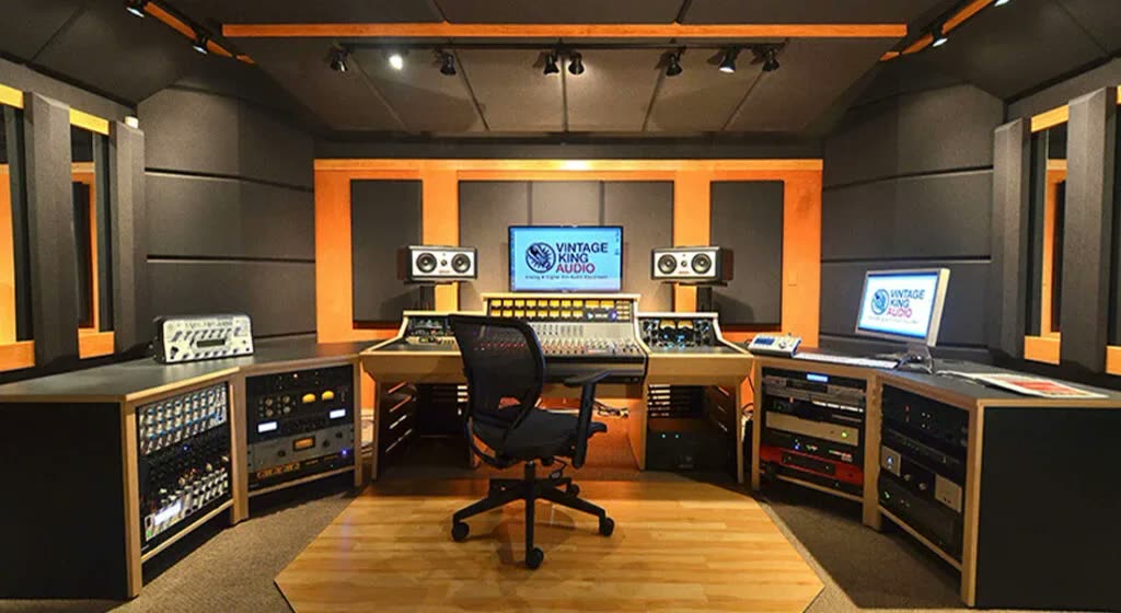 Ses kayıt stüdyosu kontrol odası: duvar/tavanda akustik emici paneller, mikser masası ve monitör hoparlörler